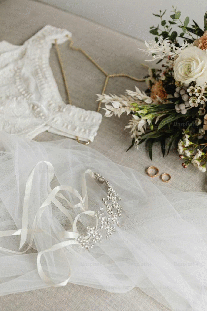 A white wedding gown on a hanger, along with flowers and accessories