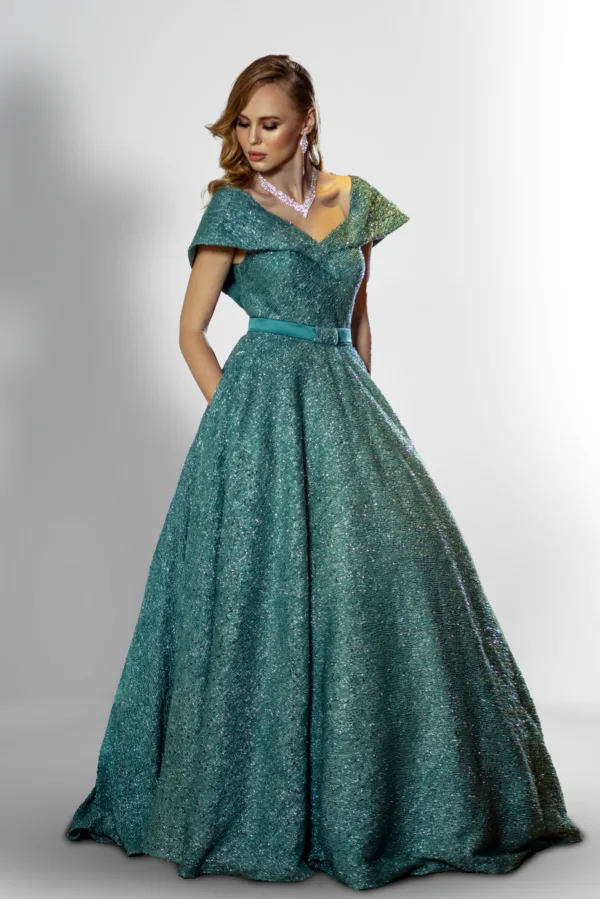 Woman wearing an elegant teal couture ball gown with a structured off-shoulder neckline, belted waist, and sparkling textured fabric