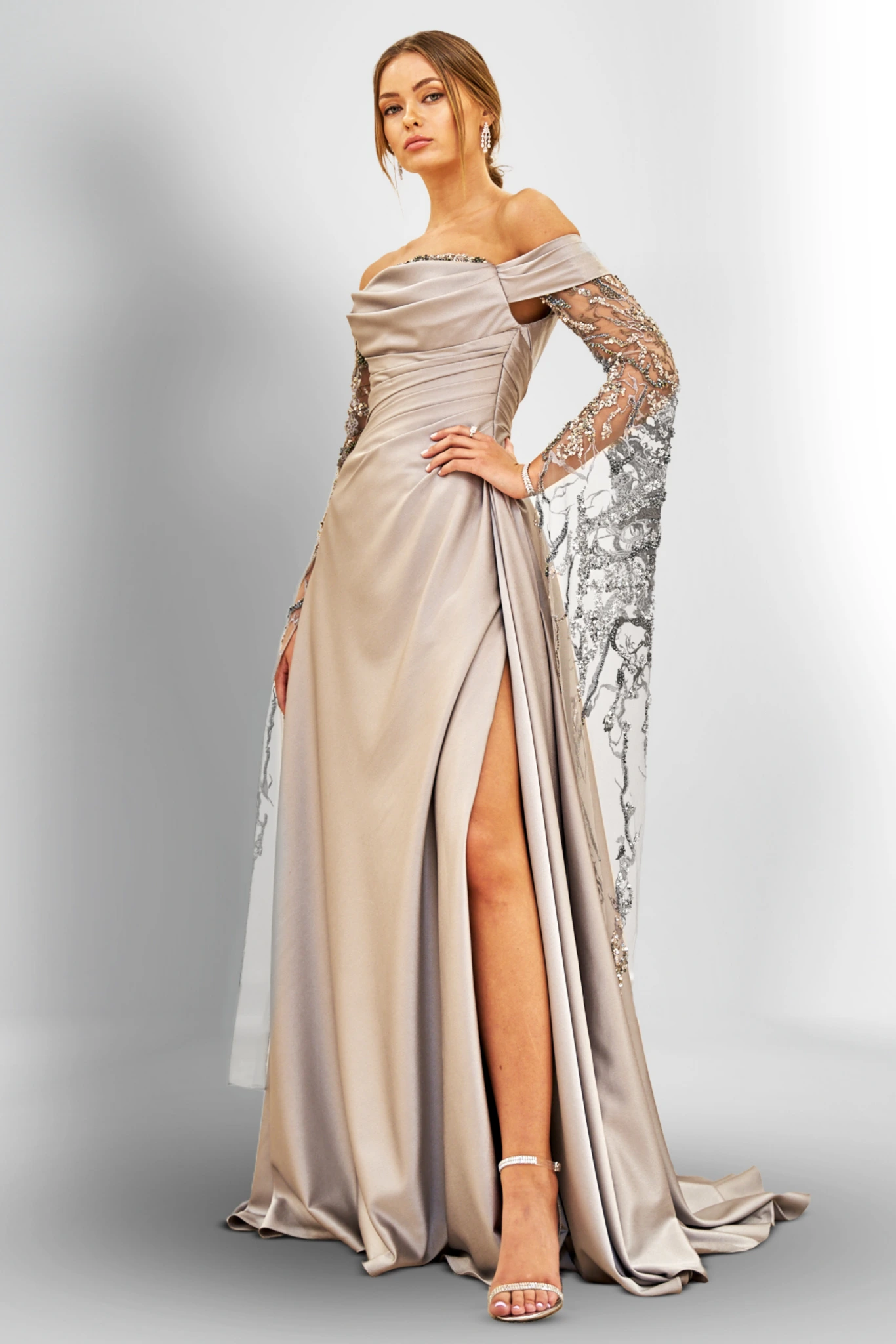Woman in an elegant off-shoulder gown with slit and embroidered sleeves.