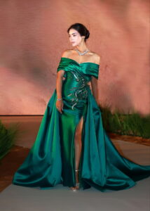 Model wearing an elegant emerald green off-shoulder gown inspired by international fashion trends, representing modern UAE style.